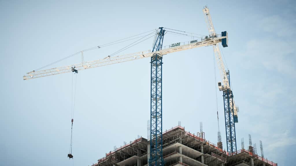 Maxim crane rental in the sky with a building a blue sky in the backround