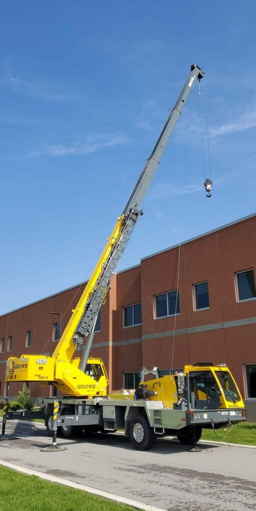 Hydraulic crane working on a building project with the boom and hook in the air..