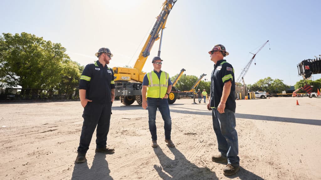 Maxim Crane engineers standing in front of a Maxim crane rental yard.