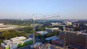 Tower cranes working on a project with a city in the background and lots of foliage.