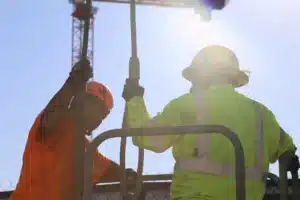 Construction workers using rigging equipment collaborate at sunset, showcasing teamwork and dedication on the job site.
