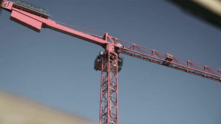 Red construction crane against a clear blue sky, showcasing height and industrial strength.