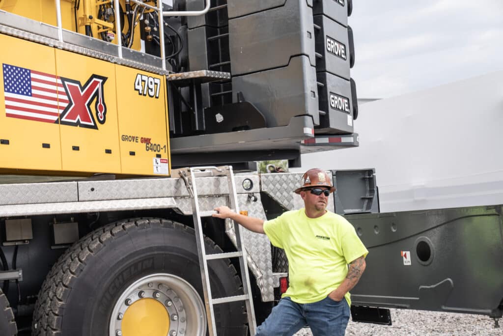 Grove GMK 6400-1 crane overview with operator in safety gear and vibrant yellow shirt.