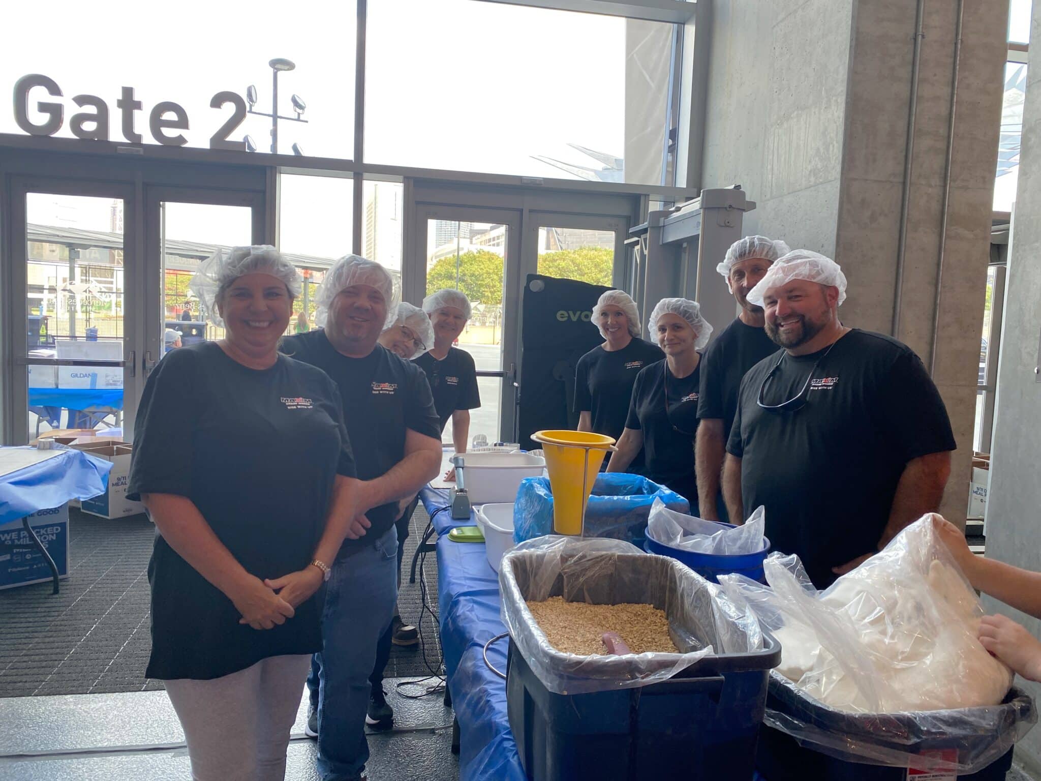 Maxim Crane Volunteers prepare meals together during 9/11 Week of Service, fostering community and teamwork.