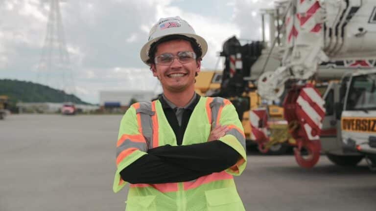 Maxim Intern Miles in safety gear smiling at construction site, showcasing safety practices.