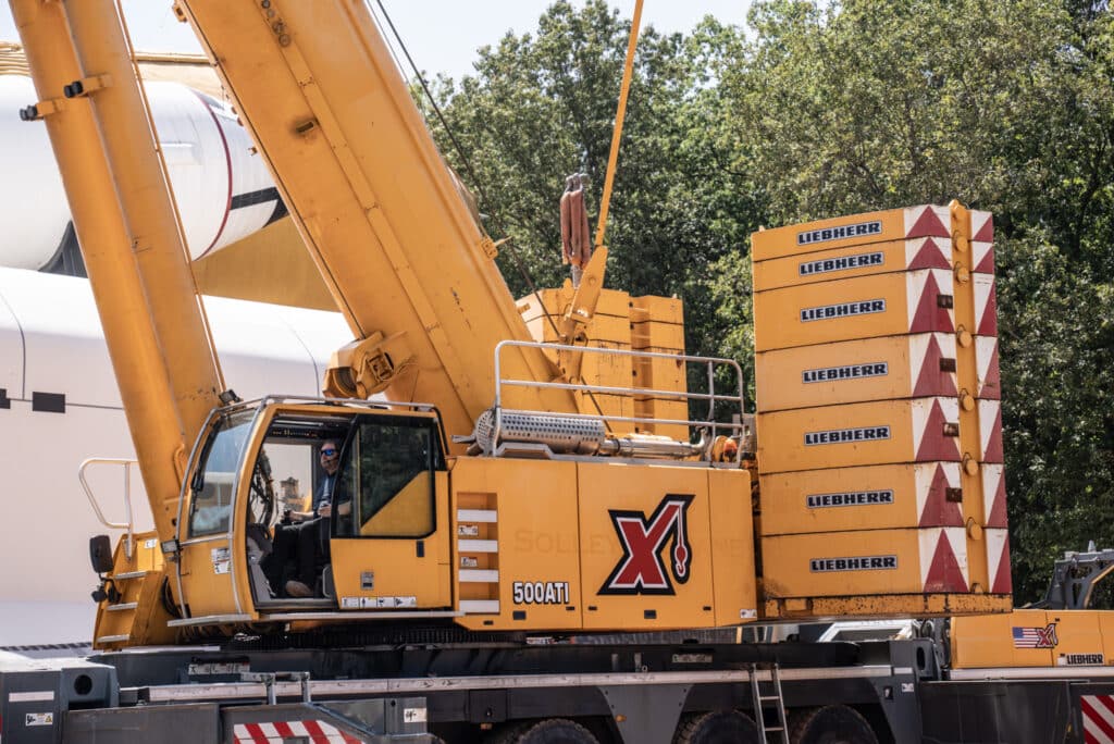 Maxim Liebherr crane efficiently lifting materials at a busy construction site.