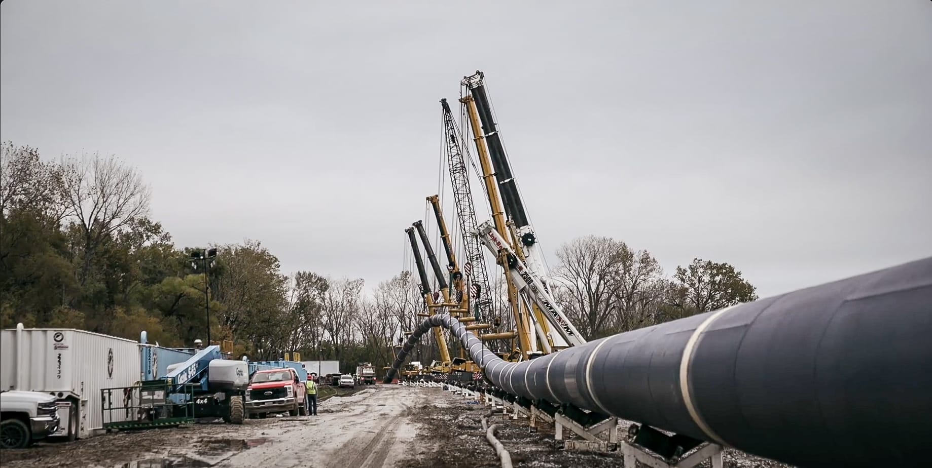 Construction machinery working on pipeline installation under overcast skies.