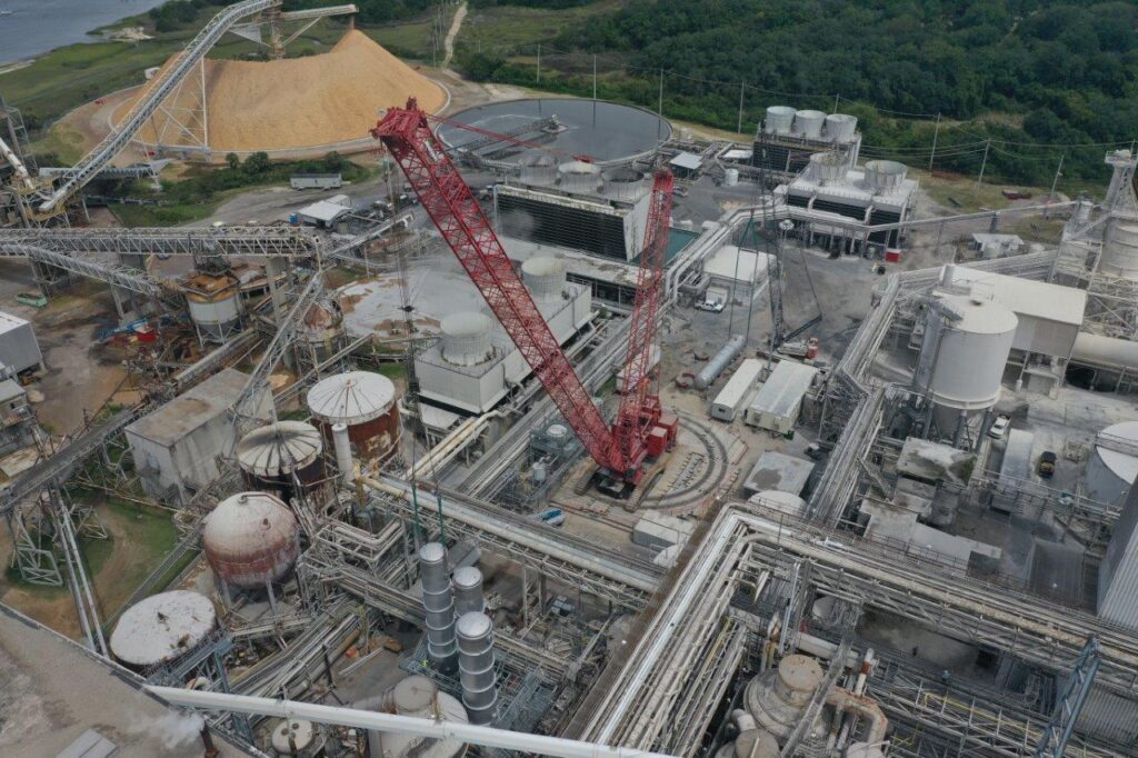 Red Maxim crane at industrial site overseeing machinery and storage operations.