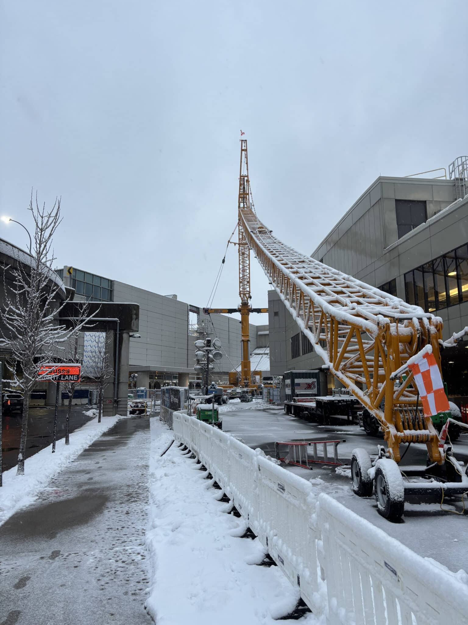 Snow-covered crane at Boston Logan Airport during winter construction.