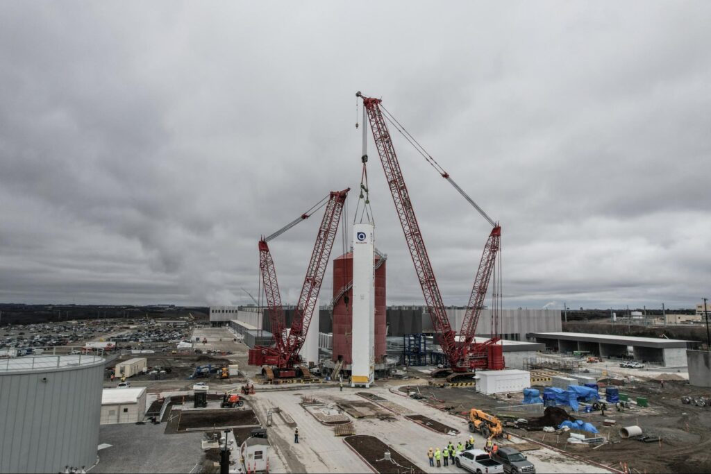 Heavy cranes work efficiently at a construction site under overcast skies.