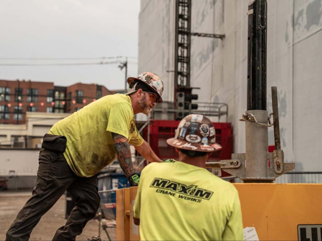Maxim Crane workers collaborate on a job site while ensuring safety and efficiency.