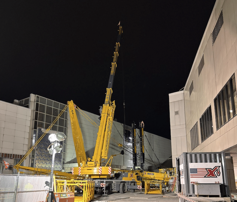 Cranes and machinery operating at a construction site under the night sky.