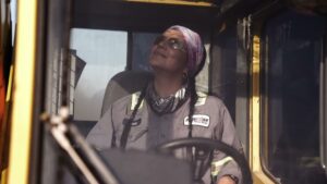 Confident woman crane operator showcasing women’s empowerment in construction at Maxim Crane Works.