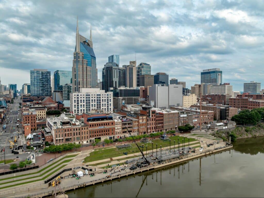 Nashville skyline featuring modern buildings and a river view under dramatic clouds.