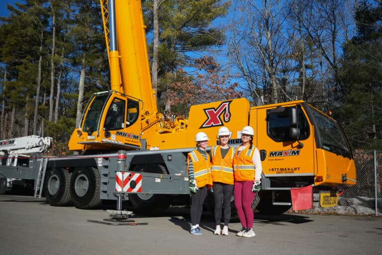 tudent Visionaries participants at Maxim pose proudly beside a bright yellow crane.