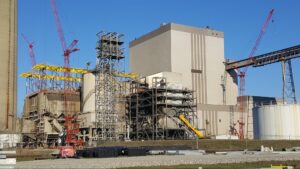 Power plant construction site featuring cranes, scaffolding, and large industrial structures.