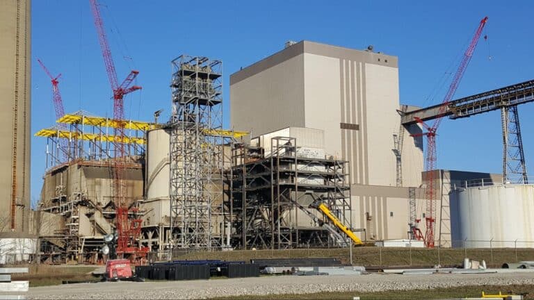 Power plant construction site featuring cranes, scaffolding, and large industrial structures.