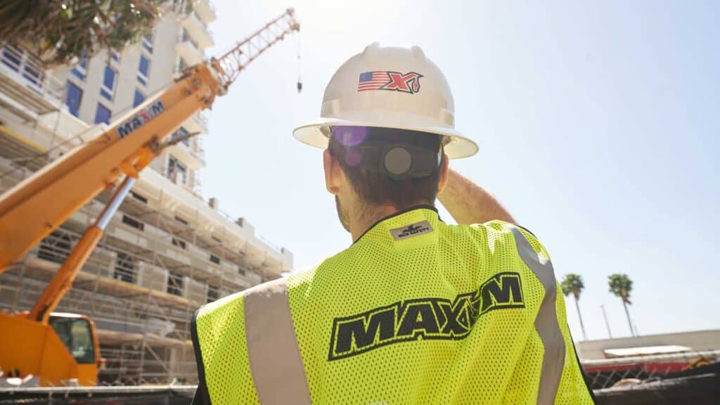 Construction supervisor overseeing crane operations on a bright, busy job site.