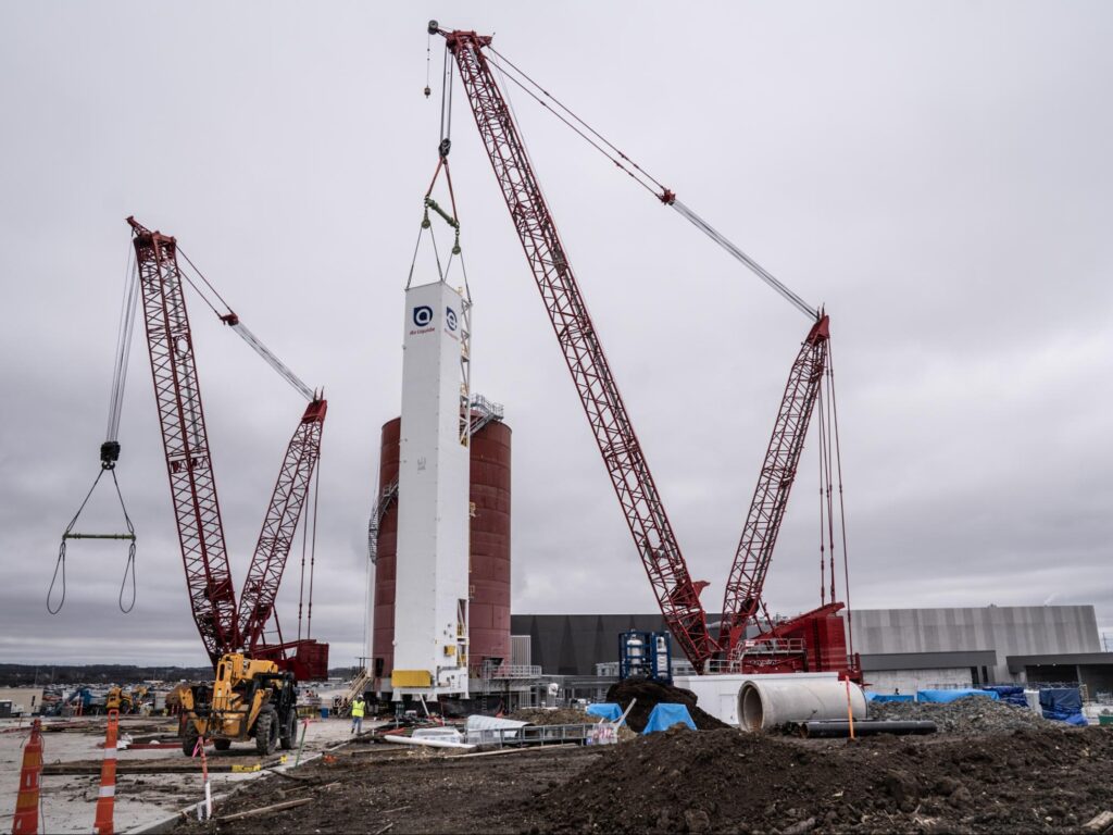 Heavy machinery lifting components at a large-scale construction site.