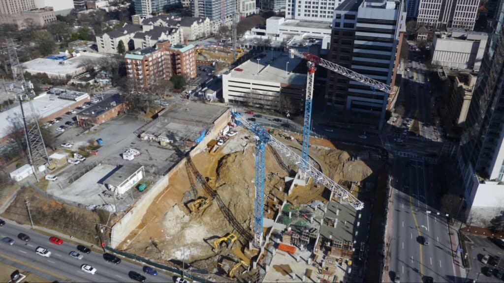 Aerial view of urban construction site with cranes and heavy machinery operating.