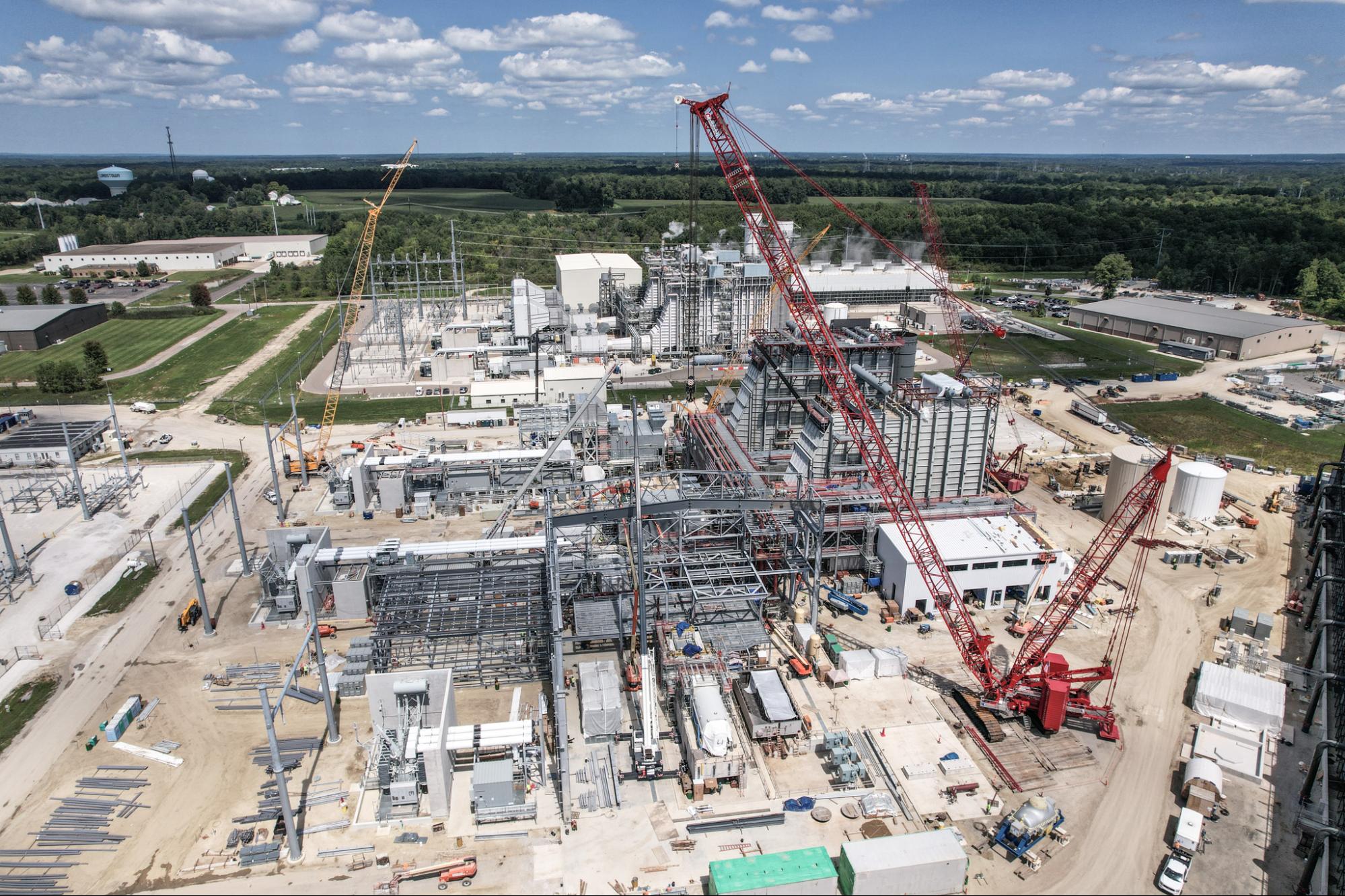 Cranes operating at a busy construction site under a bright blue sky.