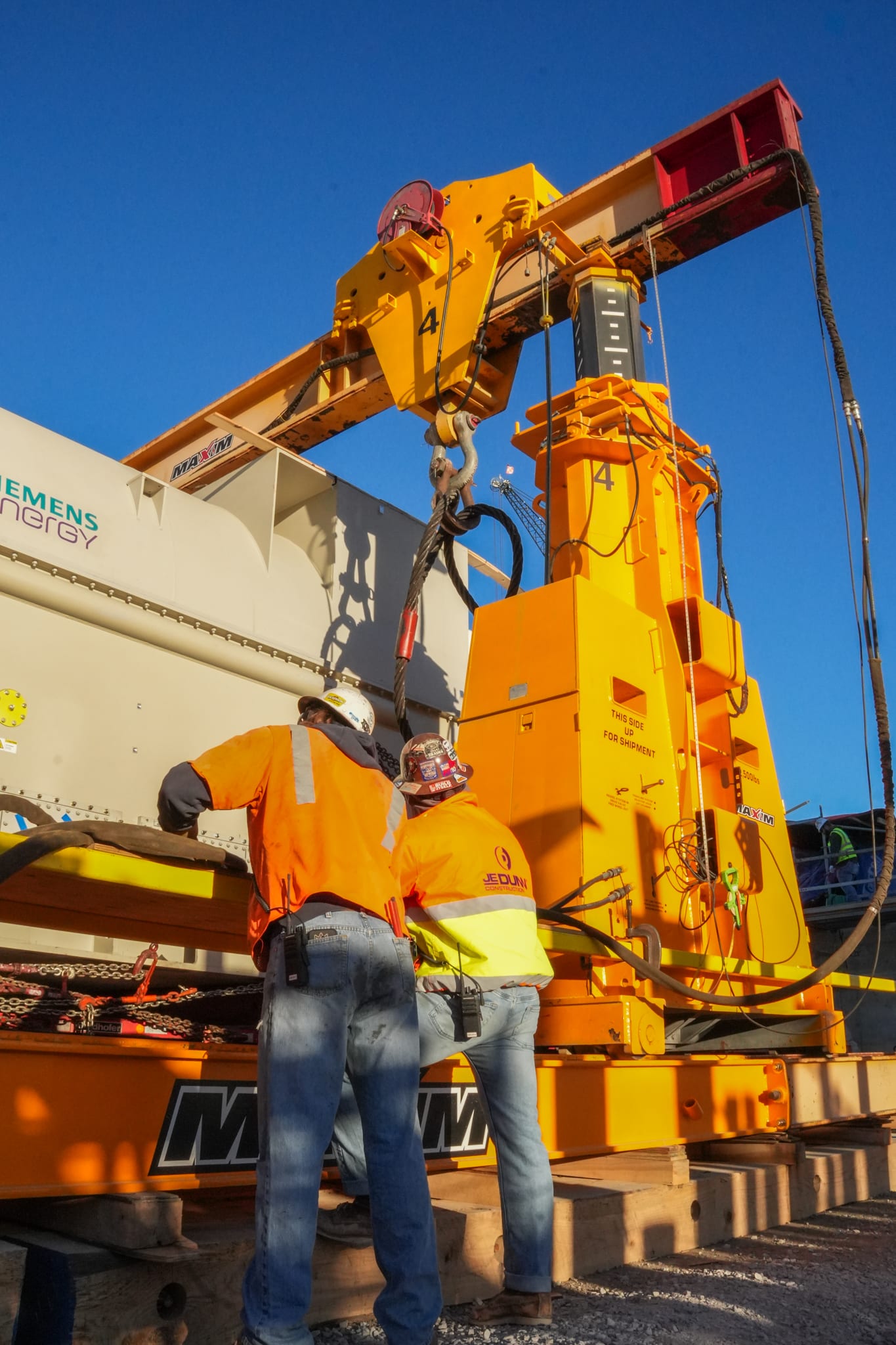 Construction workers operate a crane, showcasing heavy machinery in action.