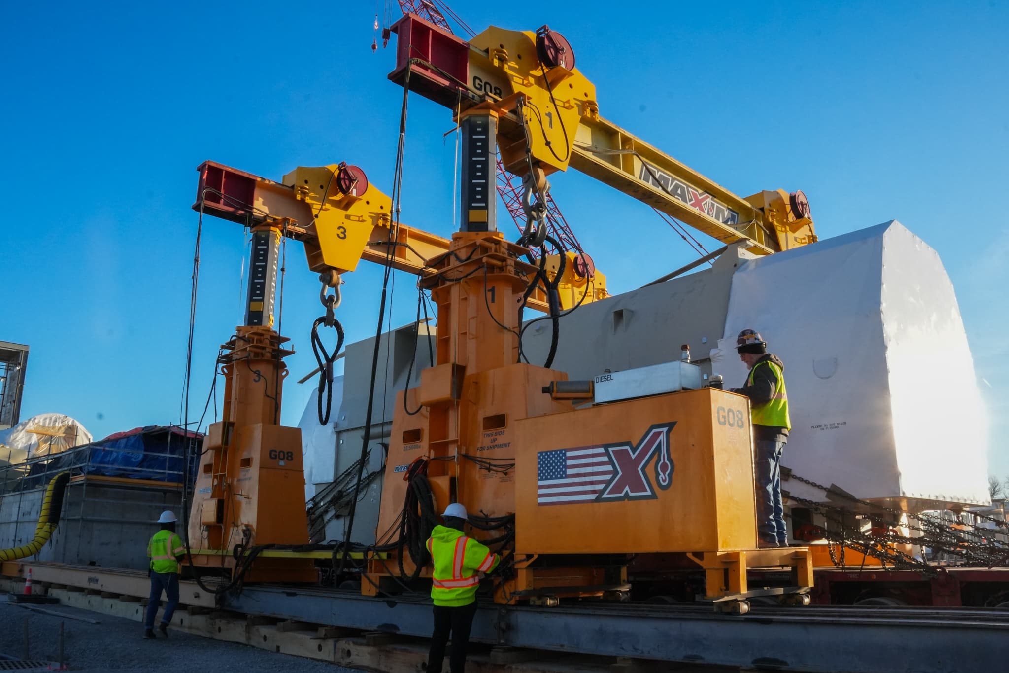 Construction cranes operating at sunset for heavy lifting and site development.