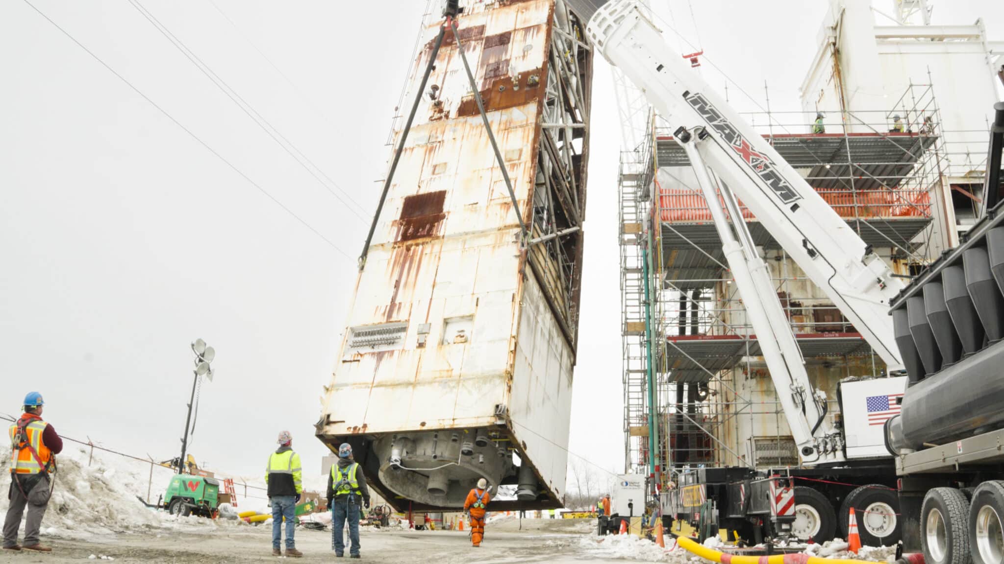 Crane lifting heavy structure at construction site, showcasing safety and precision engineering.