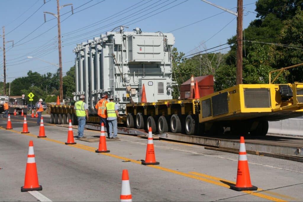 Transporting heavy equipment on urban streets with safety measures in place.