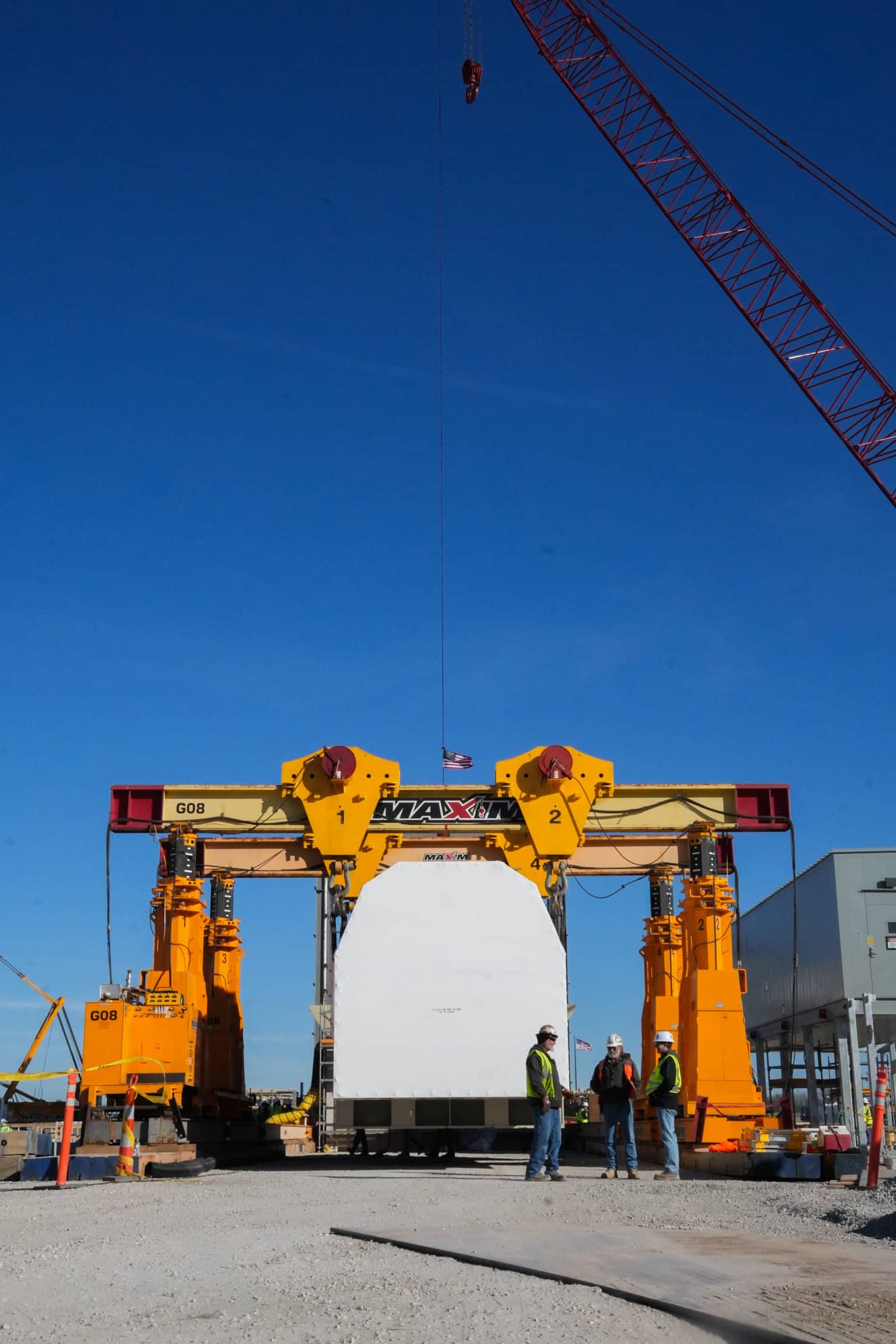 Heavy equipment transportation using a crane at a construction site.