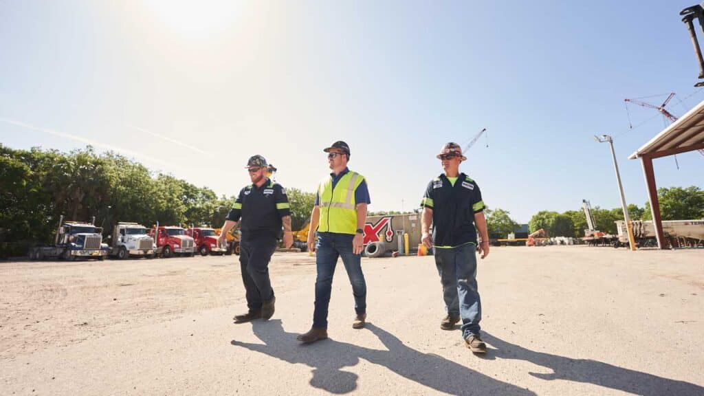 Construction workers practicing safety on site under a clear blue sky.