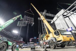 Crane setup for concert lighting at night in an outdoor stadium.