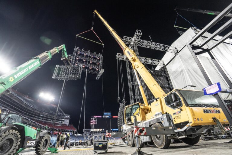 Crane setup for concert lighting at night in an outdoor stadium.