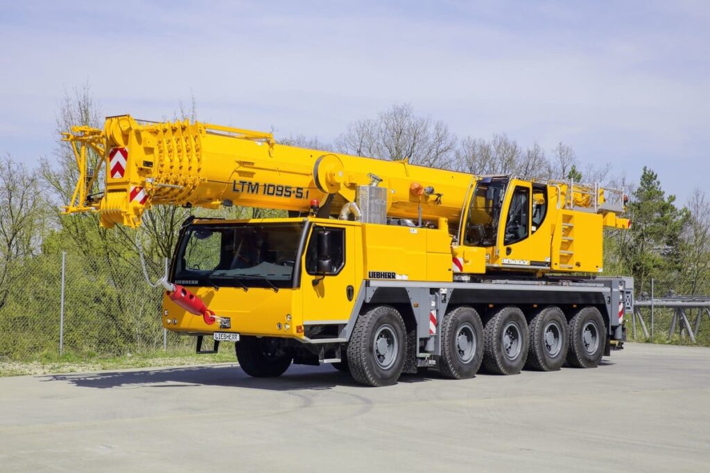 Liebherr LTM 1095-5.1 yellow crane on a construction site, showcasing mobility and strength.