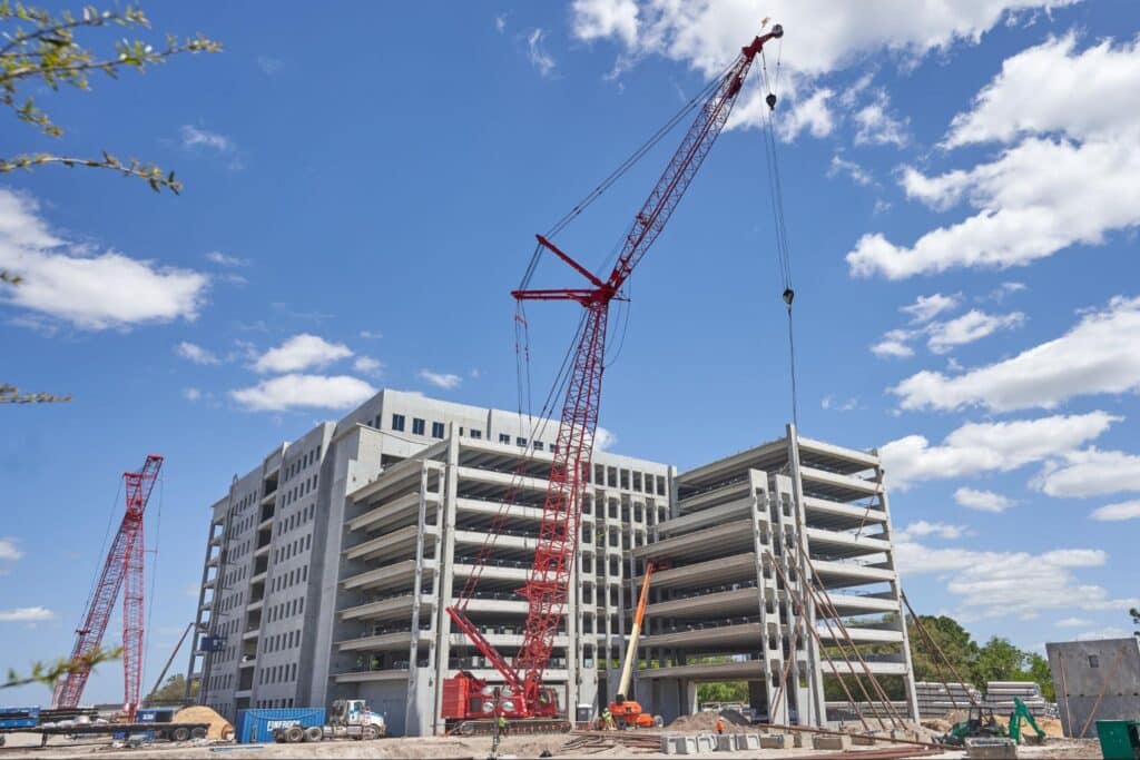 Construction site featuring a red crane and a multi-story building under development.