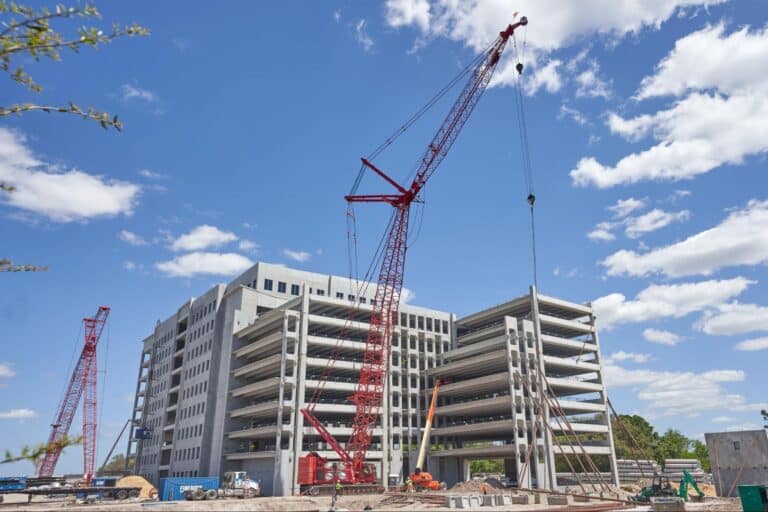 Construction site featuring a red crane and a multi-story building under development.