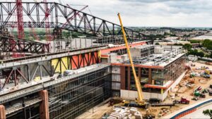 Construction site overview featuring cranes, machinery, and workers on a building project.