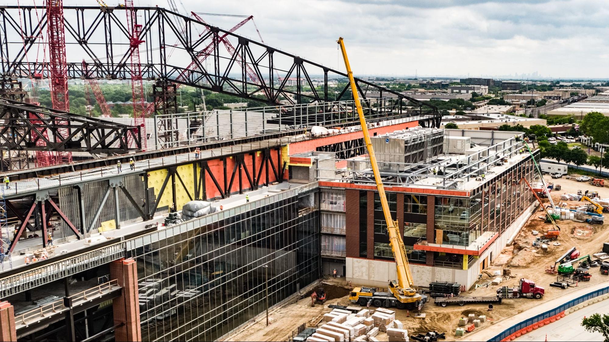 Construction site overview featuring cranes, machinery, and workers on a building project.